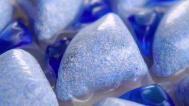 Bulaşık makinesi için toz ve sıvı mavi deterjan kapsülleri. Makro. Döndürme