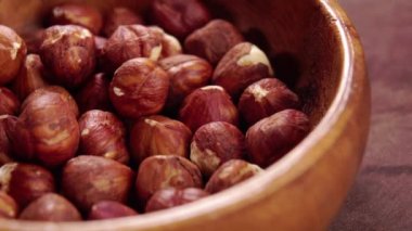 Ahşap bir arka planda, ahşap bir kasede soyulmuş fındıklar. Makro. Döndürme. Çekirdekler kapanır