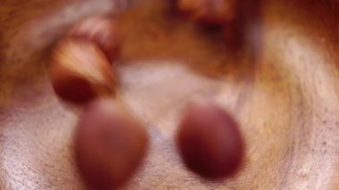 Fındık kabuğu soyulmuş çekirdekler ağır çekimde ahşap bir kaba düşüyor. Makro. Sert fındıklar.