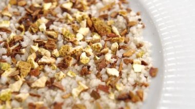 Beyaz tabakta baharatlı bitki. Kuru kardamon ve kurutulmuş limon karışımı. Makro. Döndürme