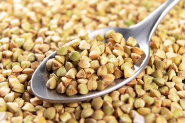 Kaşık içinde çiğ yeşil karabuğday. Pişmemiş tahıllar. Makro