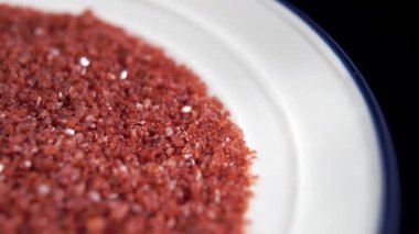 Alaea Hawai kırmızı deniz tuzu beyaz ve mavi plakalı siyah arka planda. Makro. Döndürme. Mineral baharat kristalleri