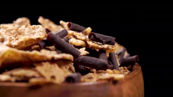 素朴な木製のボウルにチョコレートチップと小麦フレーク マクロショット 健康的なフィットネス朝食 黒を背景に — ストック動画