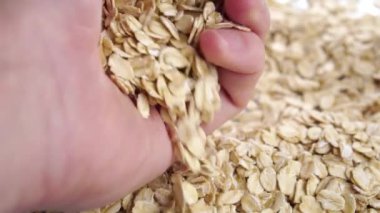 Dry oat flakes. A handful of oatmeal in hand. Falling in slow motion. Macro. Cereal dry uncooked whole grain breakfast close up