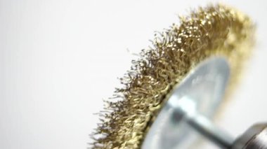 Beyaz arka planda elektrikli matkapla yeni bir pirinç tel fırça kullanarak ve döndürerek. Makro. Ağır çekim. Seçici odak