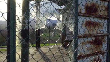 Terk edilmiş bir binanın cam penceresi, dağların arkasındaki tel örgülü tel örgülerden geçerek kırılmış. Dramatik görünüm