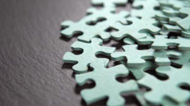 Siyah taş zeminde yapboz parçaları yığını. Makro. Döndürme. Yaratıcılık konsepti. Çocuk eğitimi oyunu bölümleri