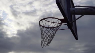 Bulutlu gökyüzünde çember ve ağ olan eski basketbol tahtası. Bulutlu dramatik görünüm