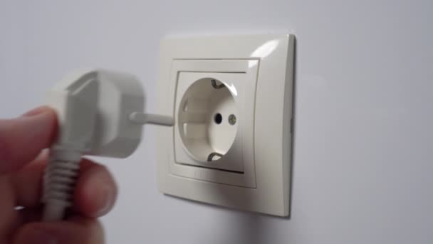 白い家庭の壁に電気ソケットに電源プラグを差し込みます 接続を切って 家庭用電気の概念 — ストック動画