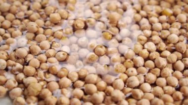 Nohut çekirdeğini yavaş çekimde suya düşürmek. Yemek pişirme ve sırılsıklam baklagiller. Yakın plan.