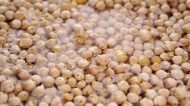 Nohut pişiriyorum. Kuru fasulyeyi yavaş çekimde suya düşürmek. Geleneksel yemekleri hazırlıyorum. Sırılsıklam baklagiller. Yakın plan. Döndürme