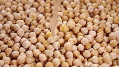 Yavaş çekimde kuru bezelyelerle bir kaseye su dökmek. Yakın plan. Kurutulmamış kuru garbanzo fasulyelerini yıkamak ve ıslatmak. Geleneksel yemekler pişirmek. Döndürme