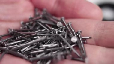 Demir çiviler ağır çekimde avuç içine düşer. Makro atış. Marangoz metal ekipmanları. Yavaş çekim