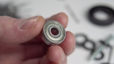 Servis elemanının elinde küçük bir çelik taşıyıcı var. Makro. Yedek parçaların arkaplanına ve bulanık tamir araçlarına karşı