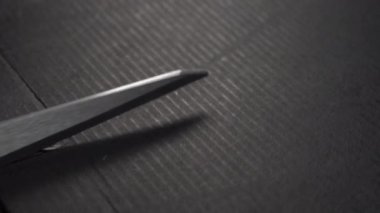 Sert desenli siyah kağıdı makasla kesiyor. Grunge karton çarşafı çizmiş. Makro