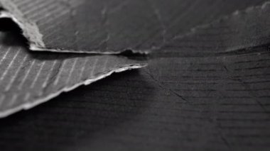 Yırtık desenli siyah kağıt. Buruşmuş mukavvanın yırtık kenarları. Makro. Döndürme