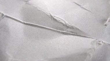 Gri buruşuk karton. Grunge kağıt parşömeni. Eski kırışıklıklar ve kırışıklıklar. Gri soyut arka plan. Makro. Döndürme