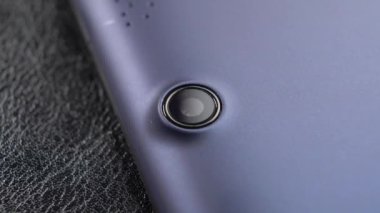 Mavi tablet web kamerası lensi siyah deri yüzeye yakın çekim yapıyor. Makro. Işık hareketi. Çevrimiçi internet sohbet kavramı