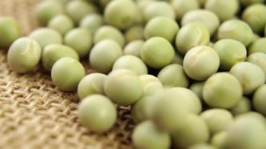 Kuru yeşil bezelyeler. Kırsal bir kumaşın üzerine kurumuş baklagiller düşmek. Makro. Yavaş çekim