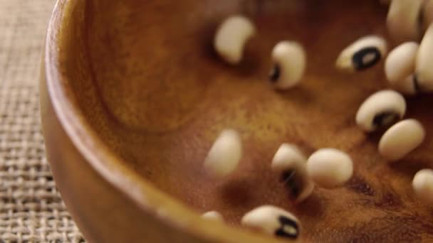 传统的卡斯蒂利亚豆 西班牙式的豆科植物以慢动作掉进一个乡村式的木碗里 米色谷物 黑眼豆 — 图库视频影像