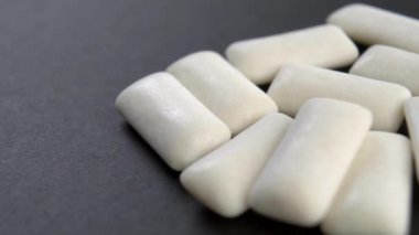 Siyah arka planda sakız çiğnemek. Makro. Döndürme