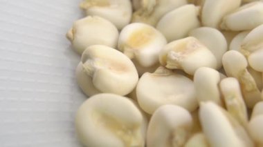 Çiğ hominy tahıl. Beyaz tabakta kuru mısır ezmesi. Makro. Döndürme