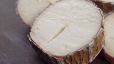 Dilimlenmiş yukka kökü. Ahşap kahverengi yüzeyde çiğ manyok dilimleri. Kurutulmuş Cassava bitkisi. Makro. Döndürme