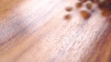 Kurumuş güvercin bezelyeleri yavaş çekimde ahşap bir kase yüzeyine düşüyor. Makro. Kuru Asya baklagilleri