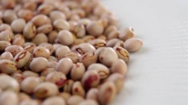 Kuru bezelyeler seramik kase yüzeyine yavaş çekimde düşüyor. Kurumuş Asya baklagilleri. Döndürme. Makro