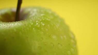 Yeşil bir elmanın üzerine su damlıyor. Yavaş çekimde taze meyve sıkmak. Ferahlatıcı bir kavram. Makro