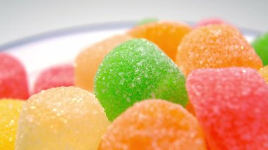 Beyaz tabakta şekerli çok renkli marmelat şekeri. Jelatin tatlı atıştırmalık. Makro. Döndürme