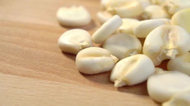 Kurumuş bir hominy. Kuru mısır, tahılı tahta yüzeyde eritiyor. Makro. Dolly vurdu.