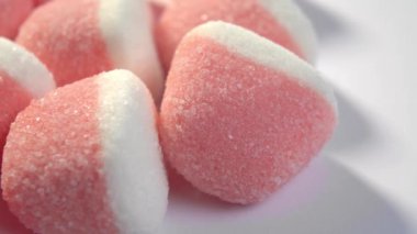 Beyaz arka planda pembe şeker marmelatları. Kırmızı şekerli jöleli şekerler. Makro. Döndürme