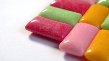 Naneli ve meyveli sakız çiğnemek. Beyaz arka planda farklı renk pedler. Makro. Döndürme