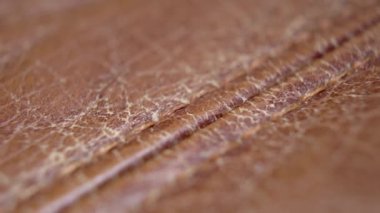 Eski püskü, kahverengi deri yüzeyi çatlamış. Dikiş yakın çekim. Makro. Dolly vurdu..