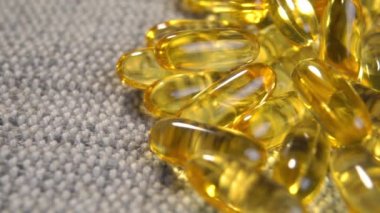 Sarı yarı saydam Omega 3 kapsülleri ve kırsal kenevir bezinde balık yağı takviyesi. Alternatif tıp konsepti. Makro. Döndürme