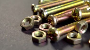 Parlak metal cıvatalar ve siyah kağıt üzerinde fındıklar. Bağlanmak için bir dizi donanım. Mekanik aletler. Makro. Döndürme