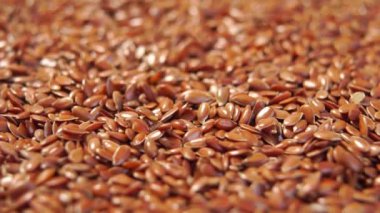 Keten tohumu yığını yaklaşıyor. Yavaş çekimde düşen kahverengi keten tohumları. Makro. Döndürme