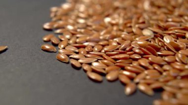 Koyu renkli ambalaj kağıdına keten tohumu yığını. Kahverengi keten tohumları. Makro. Döndürme