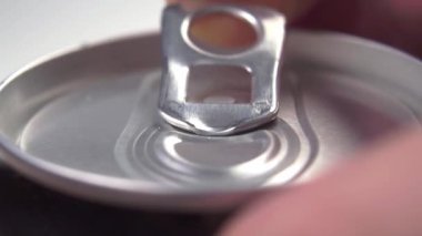 Beyaz arka planda kola içilen siyah bir alüminyum kutuyu elle açmak. Makro çekim