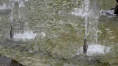 Su taştan süslemeleri olan bir şehir parkındaki silindirik fıskiyelerden akıyor ve fışkırıyor. Yavaş çekim