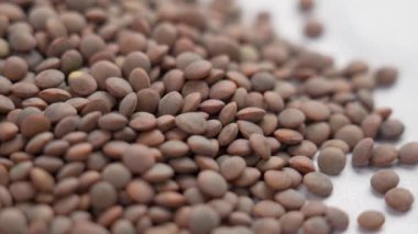 Beyaz üzerine kuru kahverengi mercimek. Baklagilleri pişiriyorum. Yavaş dönüş. Makro görünüm