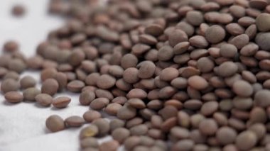 Kahverengi çiğ mercimek. Beyaz kağıtta pişmemiş baklagiller. Döndürme