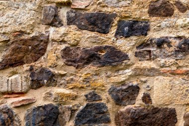 Kahverengi bir antika binanın eski, yıpranmış taş duvarı. Kaba desenli Grunge yüzeyi