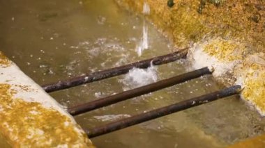 Metal ızgaralı taş bir kanala saf kaynak suyu sıçraması. Ağır çekim. Yakın plan. Ekolojik ekosistem kavramı