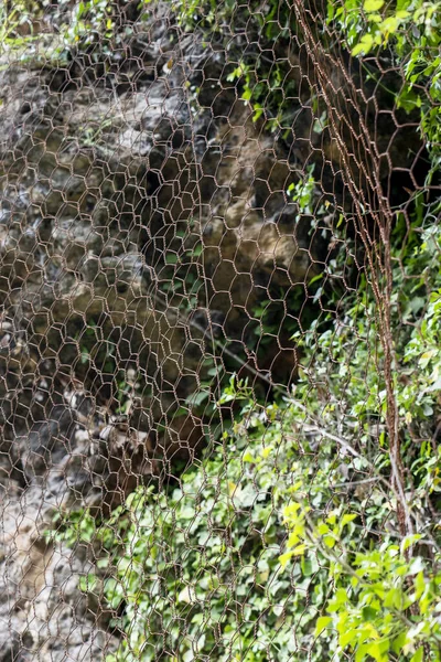 A protective metal mesh covers the rocks from rockfall. Metallic net protects the road from landslides and falling stones. Safe mountain equipment