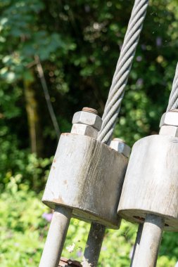 Bolt with a nut fastening the rope of a suspension bridge with a twisted steel cable close-up. Heavy engineering concept