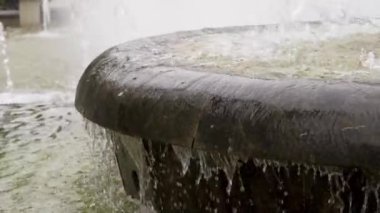Slow motion of flowing water of city stone fountain cascade closeup