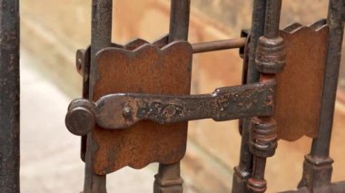 İspanya 'daki antik katedralin kafes kapısının kapalı kapısının eski metal işlemeli sürgülü sürgüsü (mandalı). Mekanik ortaçağ kilidi