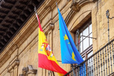 Oviedo, İspanya - 21 Temmuz 2022: Tarihi şehir merkezinin antik binası üzerinde İspanya ve Asturias bayrakları